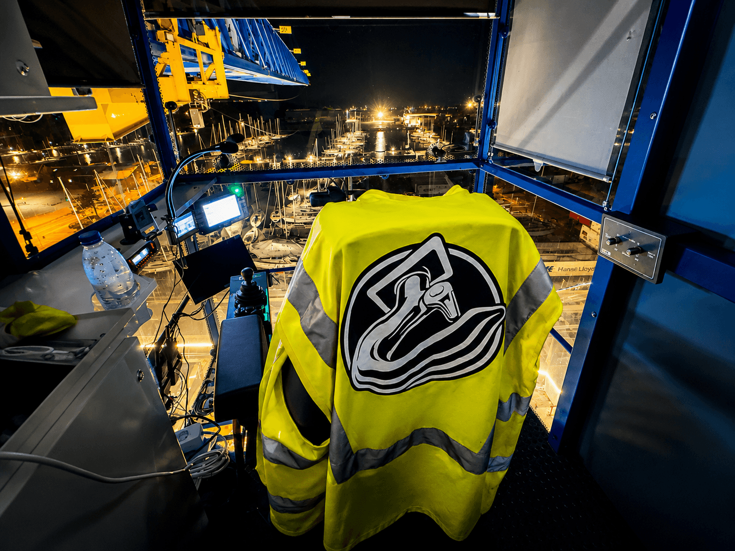 Førerplads i en tårnkran på tunnelbyggeriet i Nordhavn med KSR Cranes-logo på sikkerhedsvest og udsigt over byggepladsen om natten.